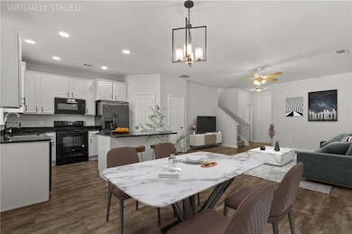Open concept dining/kitchen/living room space featuring dark wood-look laminate flooring, recessed lighting, and a modern light fixture