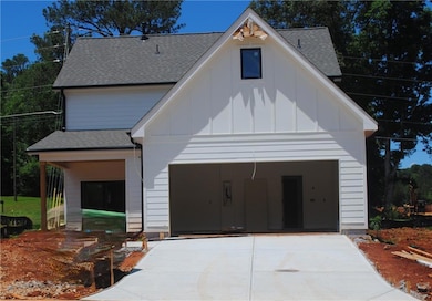 Modern farmhouse featuring board and batten siding, concrete driveway, and roof with shingles