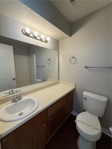 Full bath featuring vanity, dark wood-type flooring, and a textured ceiling