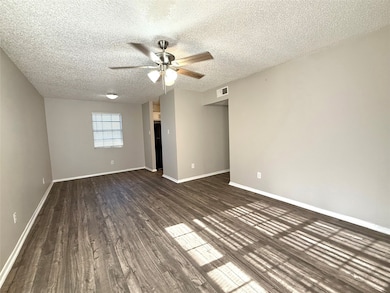 Unfurnished bedroom with a textured ceiling, dark wood-style flooring, and ceiling fan