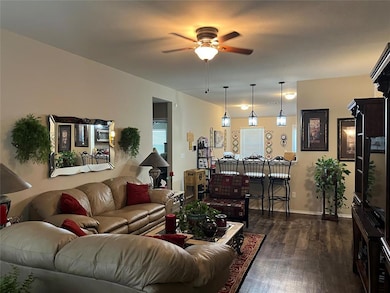 Living room featuring a ceiling fan and dark wood-style floors