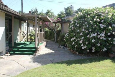 Back yard with porch and many trees and flowers
