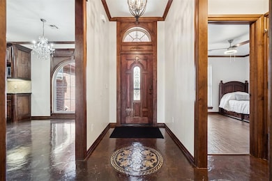 Entrance foyer with crown molding, a chandelier, plenty of natural light, and a ceiling fan