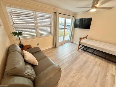Living area featuring baseboards, wood finished floors, crown molding, and ceiling fan