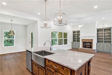 Kitchen featuring open floor plan, light wood finished floors, a center island with sink, decorative light fixtures, and recessed lighting