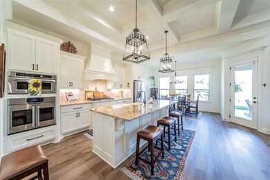 Kitchen with appliances with stainless steel finishes, backsplash, hardwood / wood-style floors, a center island with sink, and a kitchen breakfast bar