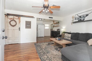 Living room with a barn door, ceiling fan, and dar