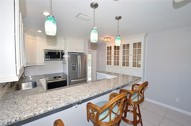 Kitchen with light stone countertops, a breakfast bar, appliances with stainless steel finishes, tasteful backsplash, and recessed lighting