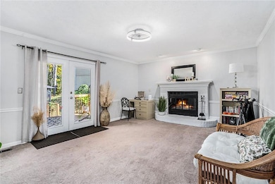 Carpeted living room featuring french doors, ornamental molding, a brick fireplace, and a textured ceiling
