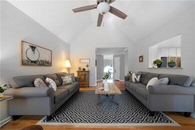 Living room featuring light wood-style flooring, high vaulted ceiling, and ceiling fan
