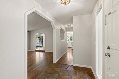 Hallway featuring wood-type flooring, a textured ceiling, arched walkways, and plenty of natural light