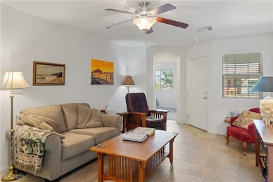 Living area featuring light tile patterned floors, ceiling fan, and arched walkways