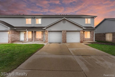 Traditional-style home featuring concrete driveway, a garage, a lawn, covered porch, and brick siding