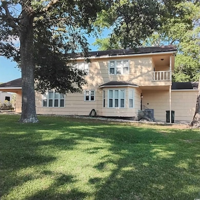 Back of house featuring a lawn, a balcony, and central AC