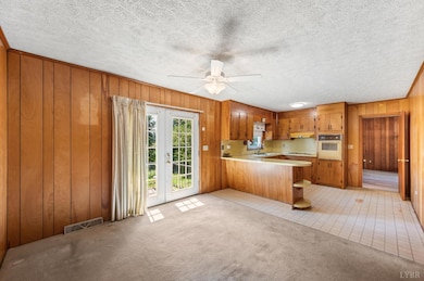 Open-concept living room and kitchen with wood paneling, island, and French doors. - 5292 Java Rd, Java, VA 24565