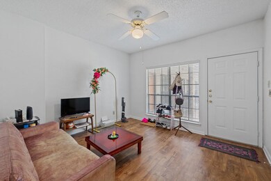 Living area with a ceiling fan, a textured ceiling, and wood finished floors