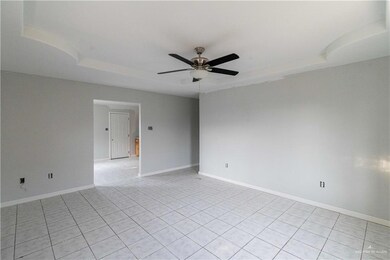 Unfurnished room with a tray ceiling, light tile flooring, and ceiling fan
