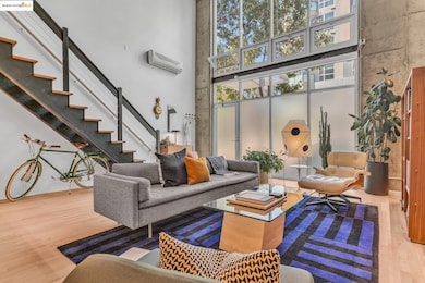 Living area featuring a towering ceiling, wood finished floors, stairway, and a wall mounted air conditioner