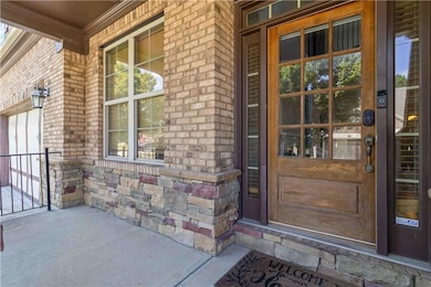 Entrance to property featuring covered porch, brick siding, and stone siding