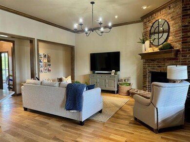 Living room with a brick fireplace, a chandelier, 