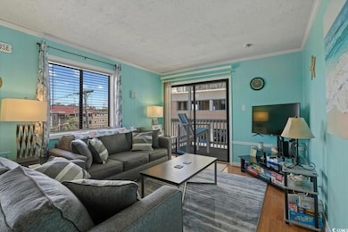 Living area with wood finished floors, a textured ceiling, and ornamental molding