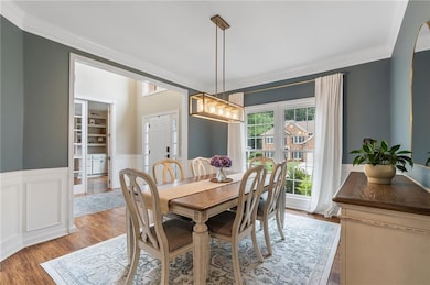 Dining area featuring crown molding, wainscoting, and wood finished floors