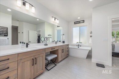 Ensuite bathroom with double vanity, a freestanding bath, and recessed lighting