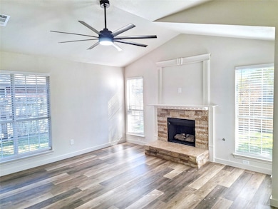Unfurnished living room featuring lofted ceiling, wood finished floors, a fireplace, and a ceiling fan