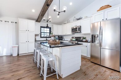 Kitchen featuring appliances with stainless steel finishes, a breakfast bar area, white cabinets, a center island, and decorative light fixtures