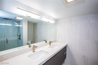 Full bathroom with a sink, tile walls, and a showe