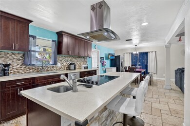 The kitchen features dark brown cabinets, light stone countertops, a center island with sink, breakfast bar, induction range, and a stylish island range hood—perfect for cooking and entertaining.