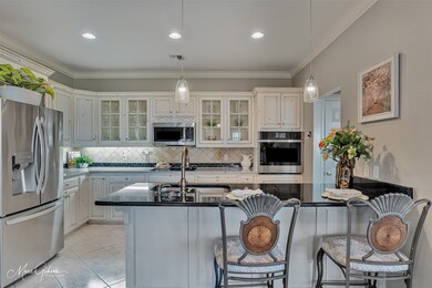 Kitchen featuring appliances with stainless steel finishes, backsplash, glass insert cabinets, dark stone counters, and ornamental molding
