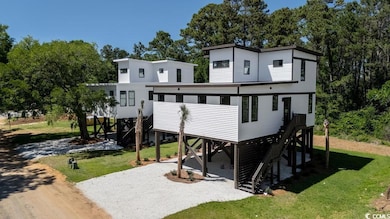 Back of house with stairs, a lawn, gravel driveway, and a carport
