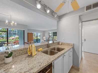 Kitchen with light stone counters, light tile patterned floors, white cabinets, visible vents, and a sink