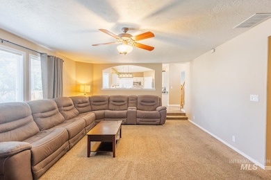Living room featuring healthy amount of natural light, ceiling fan, light carpet, and a textured ceiling