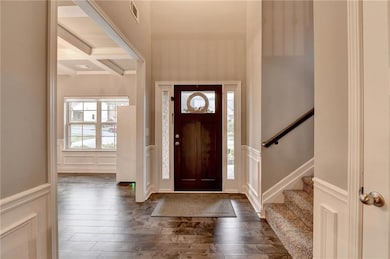 Entryway with beamed ceiling, dark wood finished floors, coffered ceiling, and a decorative wall