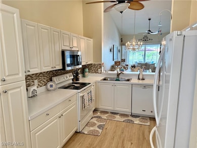 Kitchen with white appliances, a sink, ceiling fan