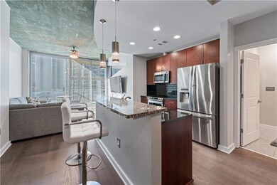 Kitchen featuring appliances with stainless steel finishes, a kitchen bar, dark stone counters, backsplash, and decorative light fixtures