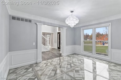 Unfurnished dining area featuring ornamental molding, a decorative wall, a chandelier, a wainscoted wall, and stairway