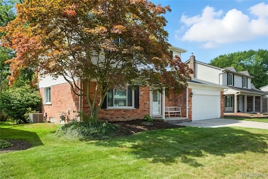 Obstructed view of property featuring brick siding, a front lawn, driveway, and a garage