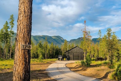 View of community featuring a forest view, a mountain view, an outbuilding, and driveway