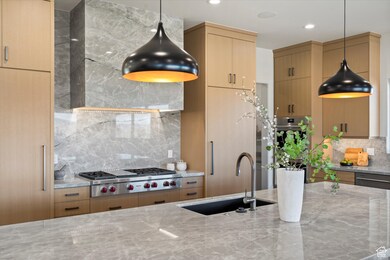 Kitchen with tasteful backsplash, pendant lighting, light stone countertops, stainless steel appliances, and recessed lighting