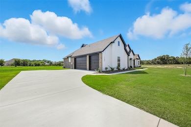 View of home's exterior featuring a yard, board and batten siding, driveway, a shingled roof, and an attached garage