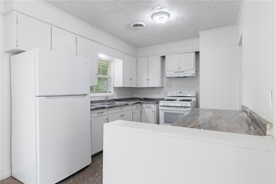 Kitchen featuring white appliances, a textured cei