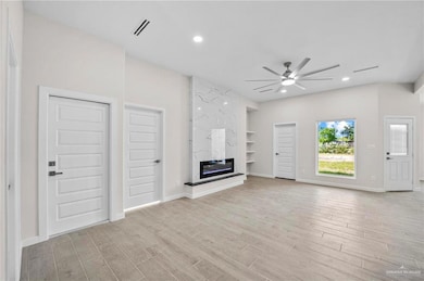 Unfurnished living room with light wood-type flooring, ceiling fan, and a premium fireplace