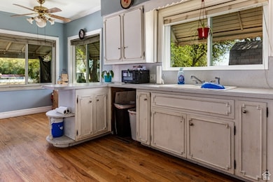 Kitchen with light countertops, open shelves, black microwave, dark wood-style floors, and ceiling fan