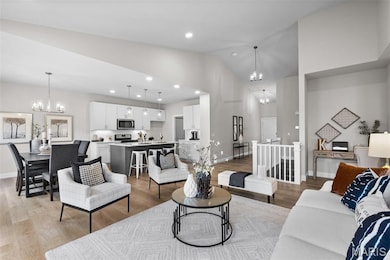Living room featuring a chandelier, vaulted ceiling, recessed lighting, and light wood-style floors