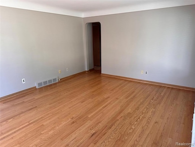 Unfurnished room with light wood-type flooring and arched walkways