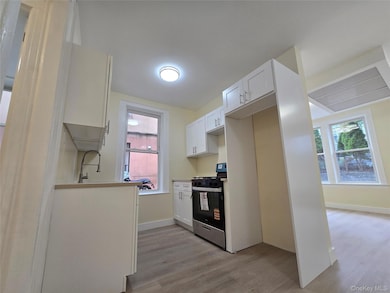 Kitchen featuring stainless steel range with gas cooktop, white cabinetry, light wood-style floors, and quartz countertops.