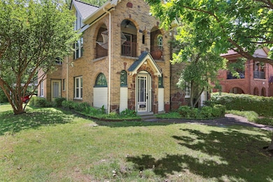View of front of property featuring a balcony, a front yard, and brick siding